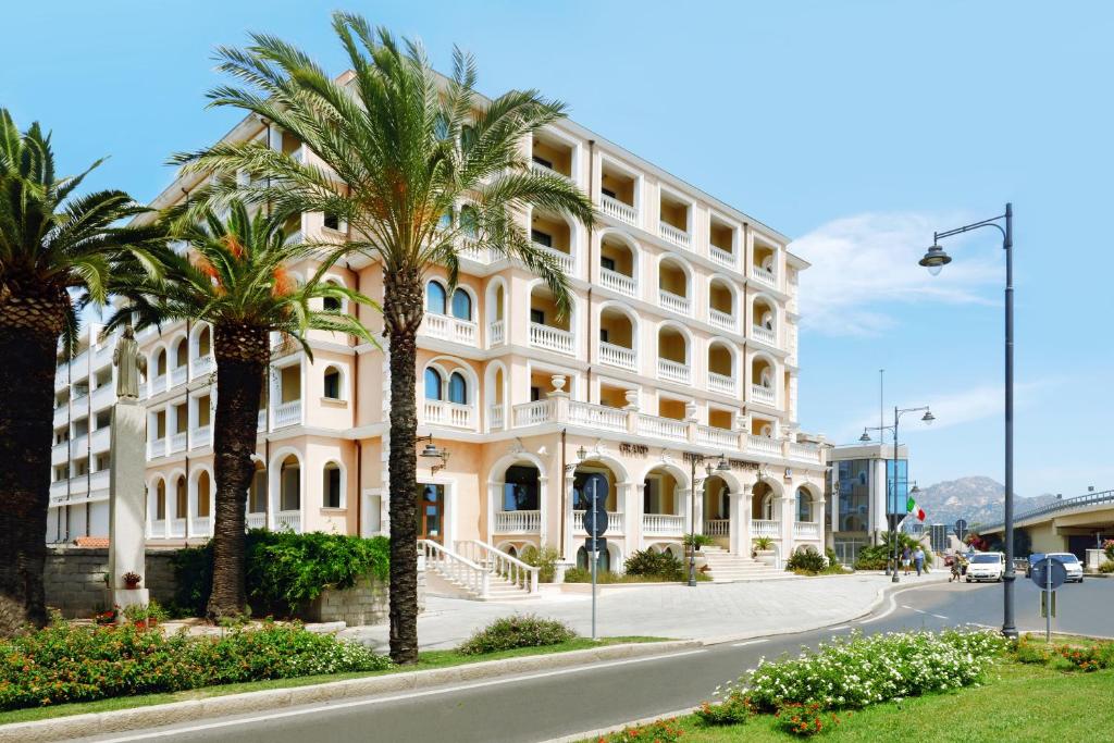 奥尔比亚总统大酒店的一座白色的大建筑,前面有棕榈树