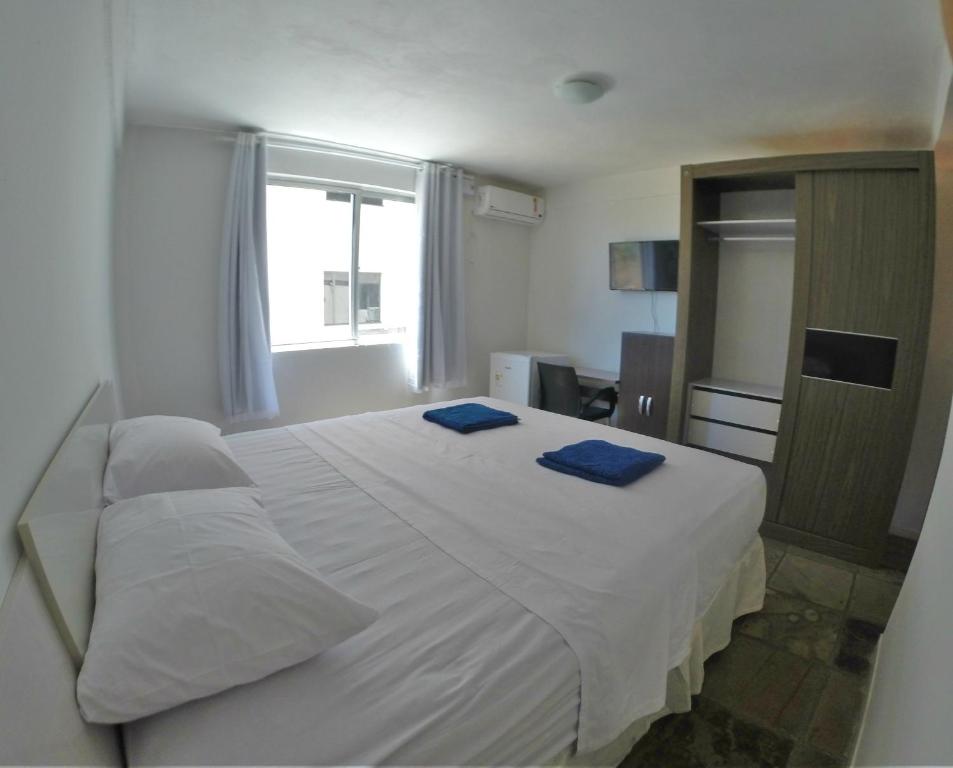 佩森Pousada Caminho do Porto的卧室配有白色床和2条蓝色毛巾