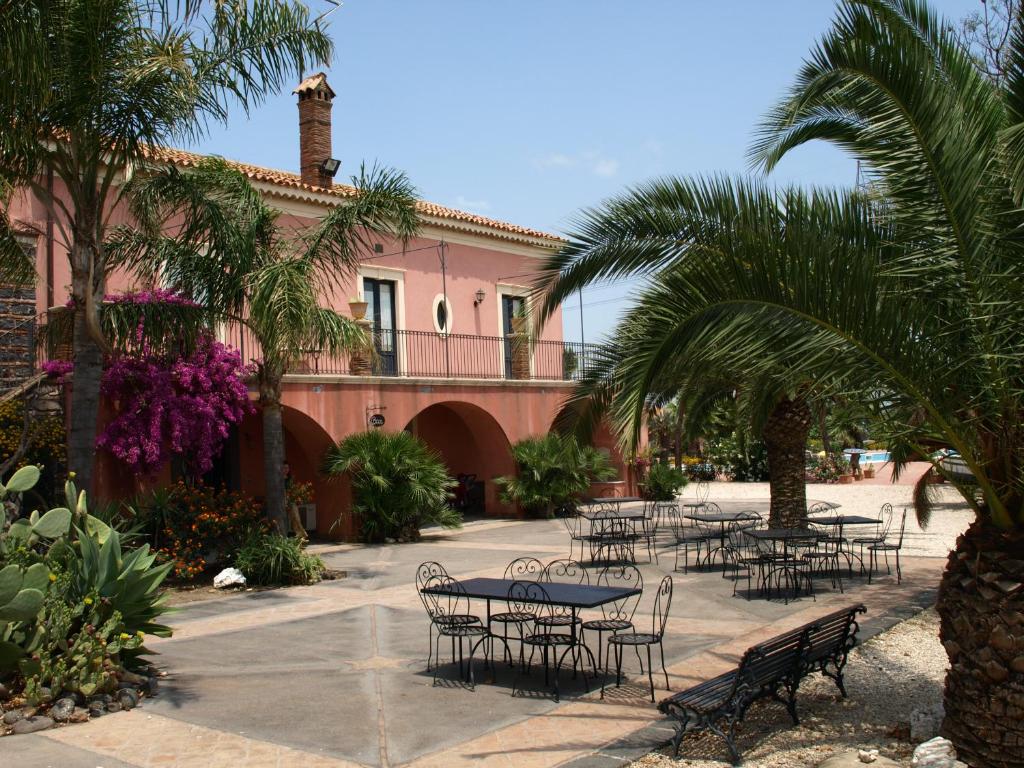 GerbiniAgriturismo Masseria Portiere Stella的一组桌子和椅子,位于一座粉红色的建筑前