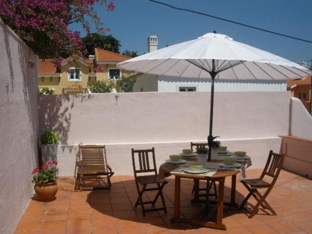 埃斯托利尔Villa Charme的庭院内桌椅和遮阳伞