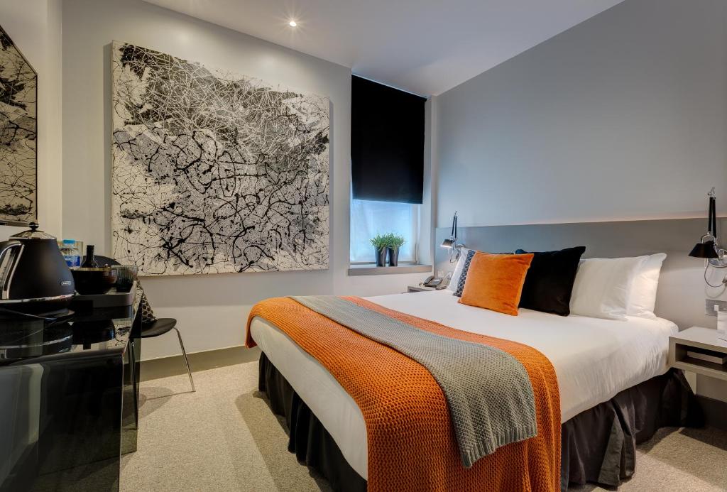 伦敦55酒店的一间卧室配有一张带橙色毯子的大床