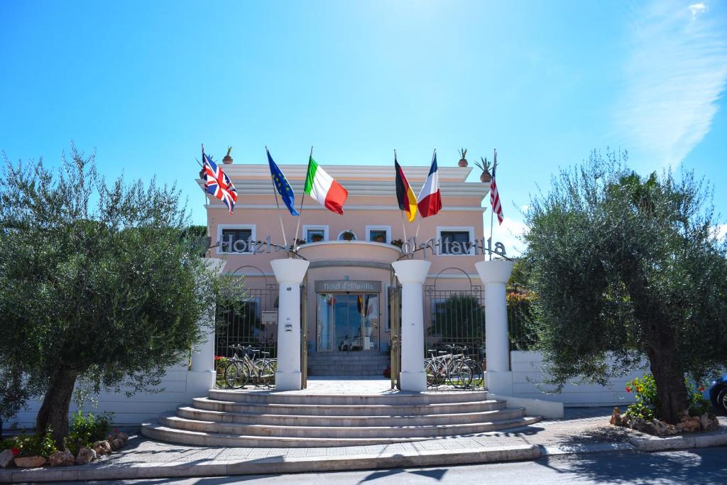 卡诺萨迪普利亚达塔微拉酒店的前面有旗帜的建筑