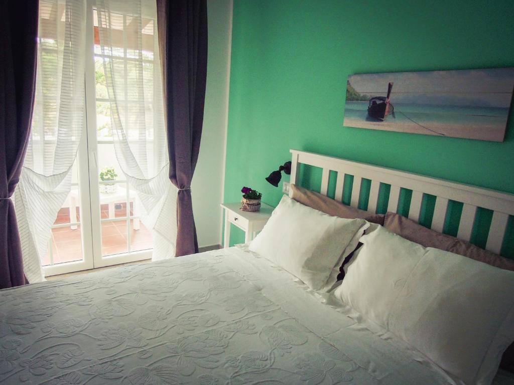 吉诺萨滨海B&B La Rosa dei Venti的一间卧室设有一张带绿色墙壁和窗户的床。