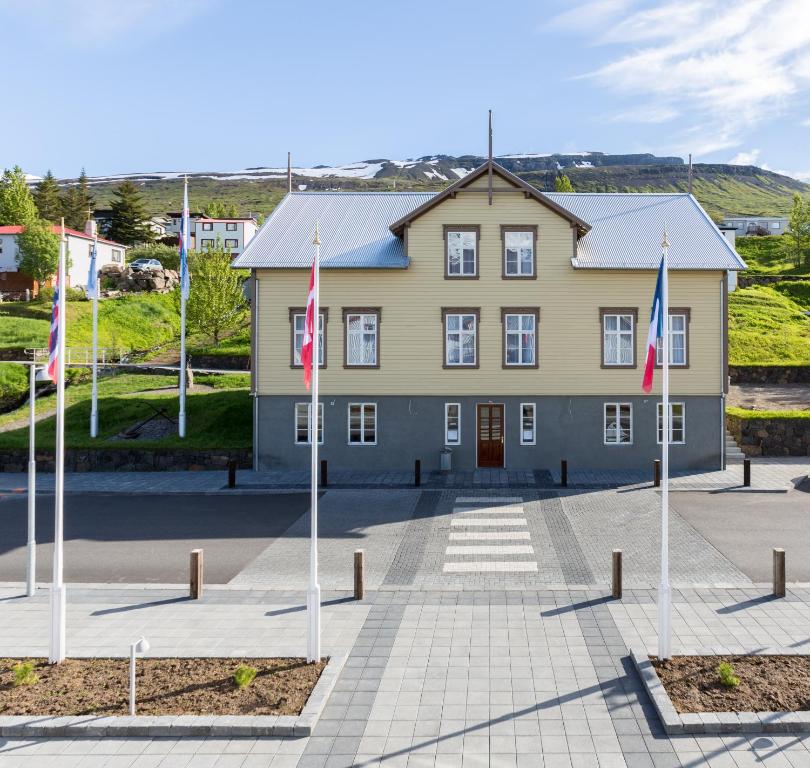 Fáskrúðsfjörður东部峡湾福斯酒店的前面有旗帜的大型黄色建筑