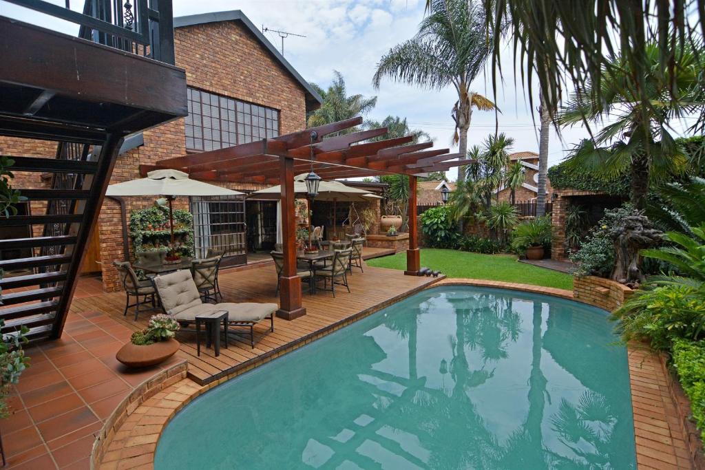 逊邱伦Africa House Guesthouse的游泳池,带桌椅的庭院