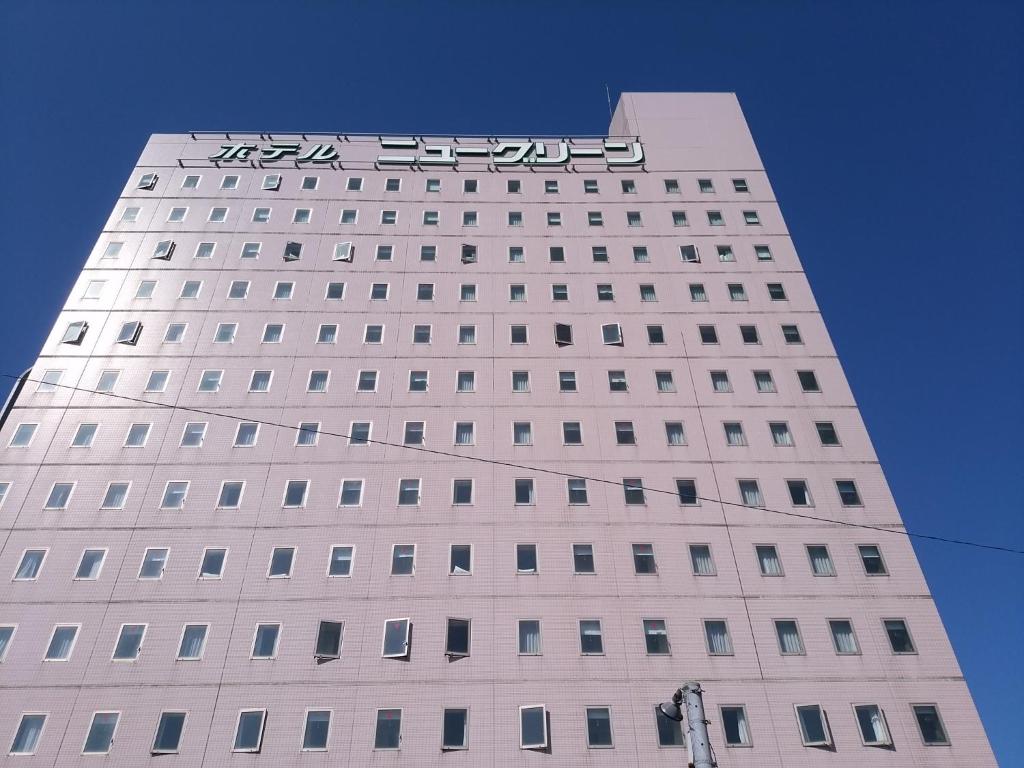 柏崎市柏崎新绿酒店的一座高大的白色建筑,上面有标志
