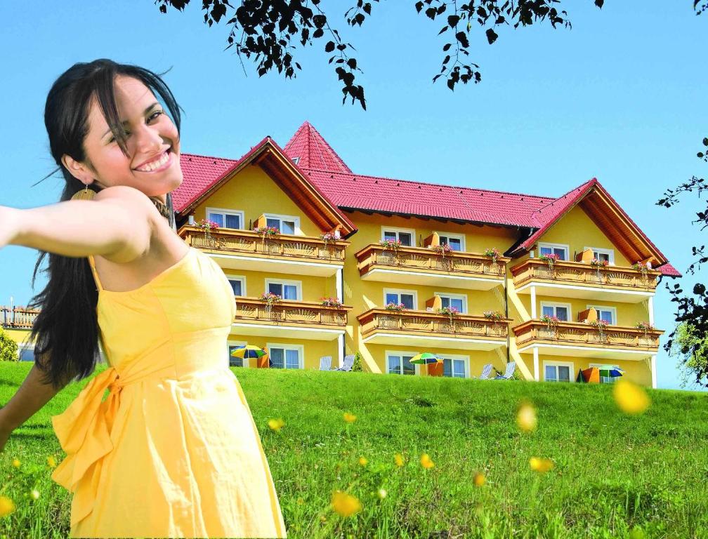 延纳斯多夫洛珀斯朵夫绿洲加尔尼酒店的身穿黄色衣服的女人在建筑物前