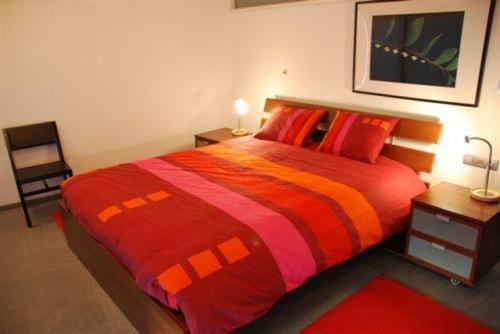 阿尔斯特马儿佩图斯公寓酒店的一间卧室配有一张大床,提供红色和橙色的毯子