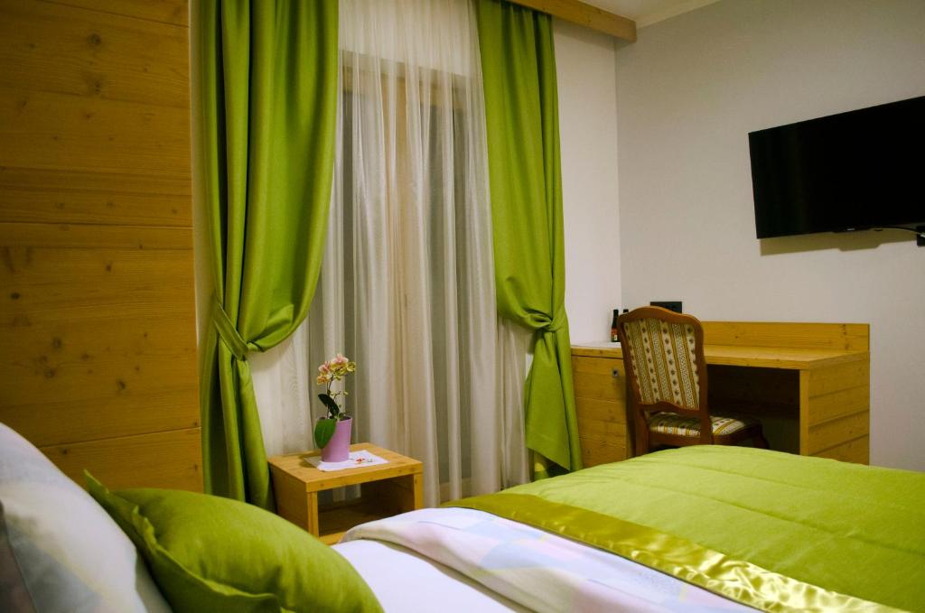 RogatecGuest House Gostišče Jutriša的一间卧室配有绿色窗帘、书桌和一张床