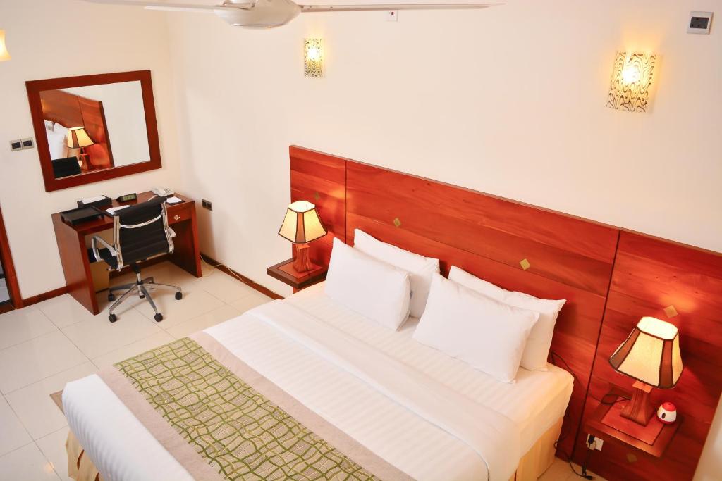 科伦坡独特大厦豪华精品套房酒店的一间卧室配有一张床、一张书桌和一面镜子