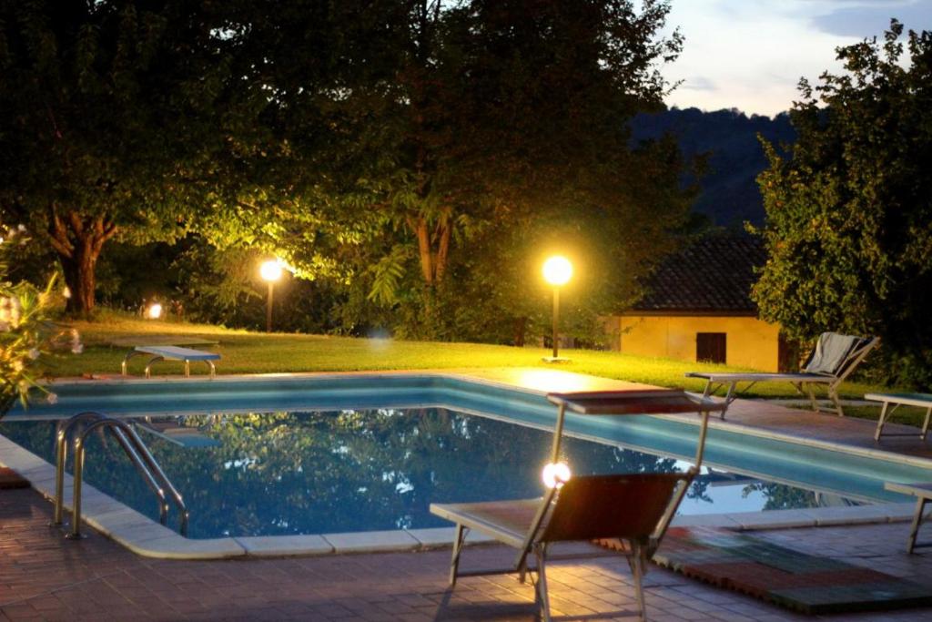 乌尔比诺Le Fontane的游泳池在晚上配有两把椅子和一张桌子