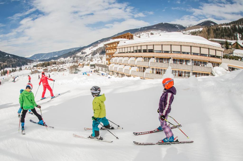 塞斯托莱纳家庭度假酒店的一群人在滑雪小屋前的雪中滑雪