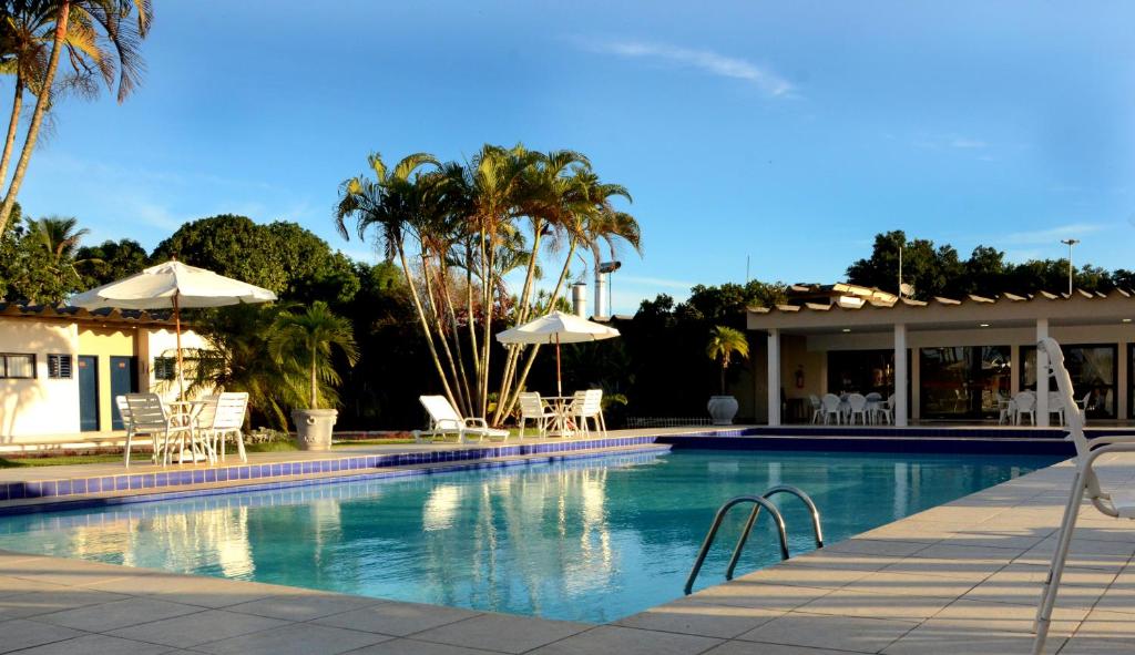 泰谢拉迪弗雷塔斯Hotel Pousada Lord的房屋旁的游泳池配有椅子和遮阳伞