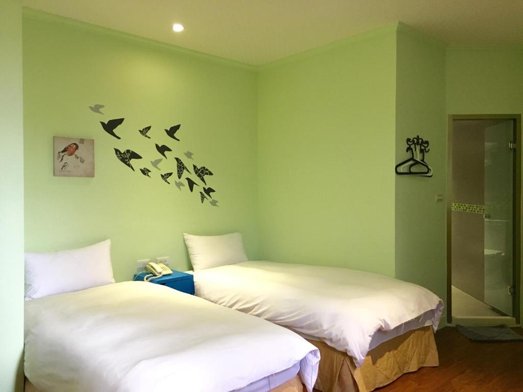 嘉义市万泰大饭店的墙上有鸟的房间的两张床