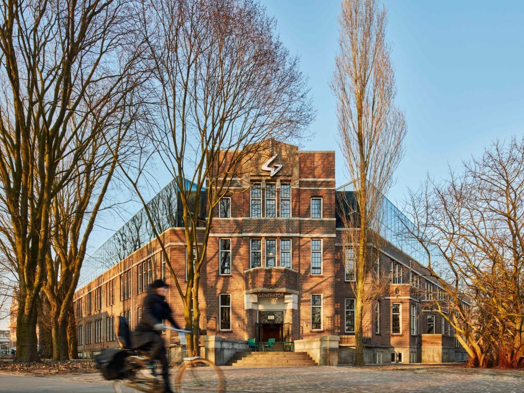 阿姆斯特丹阿姆斯特丹创造者旅舍的一个人在建筑物前骑着自行车
