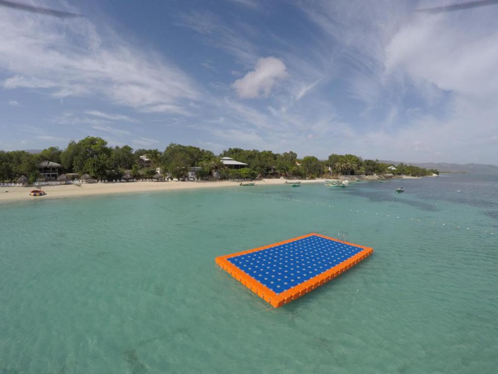 蓬塔露奇亚Paradise Island Beach Resort的海滩上水中的橙色和蓝色木筏