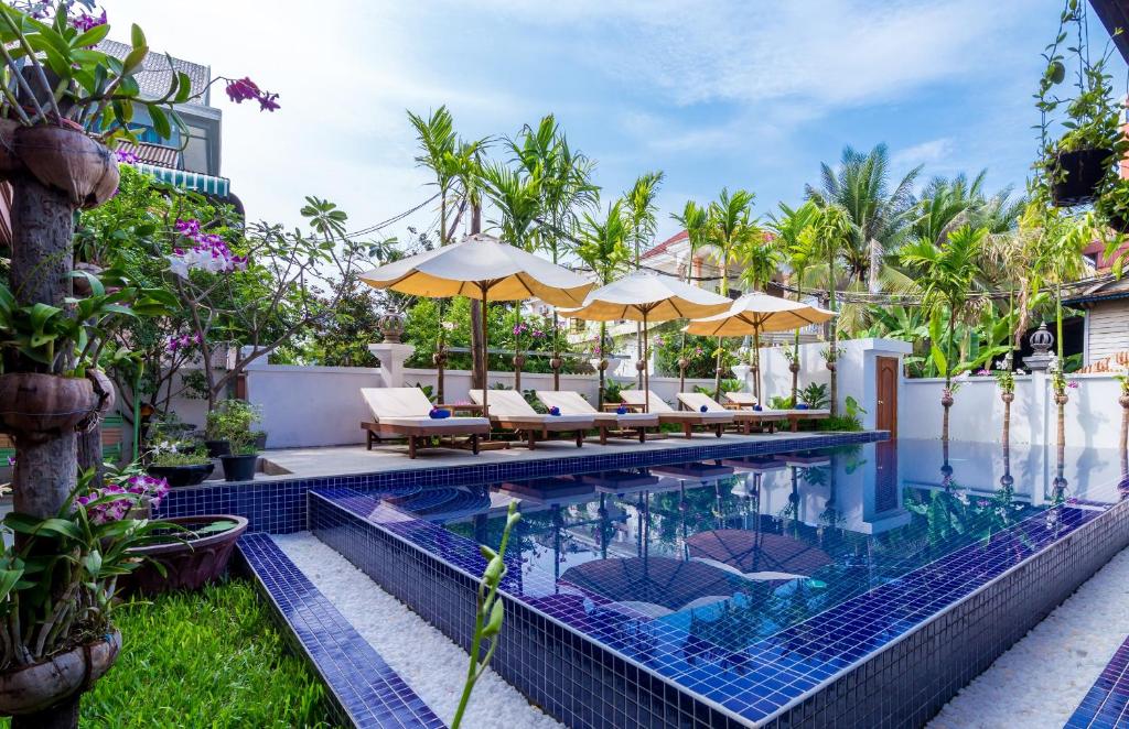 暹粒独特吴哥别墅酒店的度假村的无边泳池配有椅子和遮阳伞