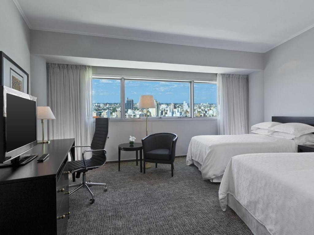 科尔多瓦Quinto Centenario Hotel的酒店客房设有两张床和一台平面电视。