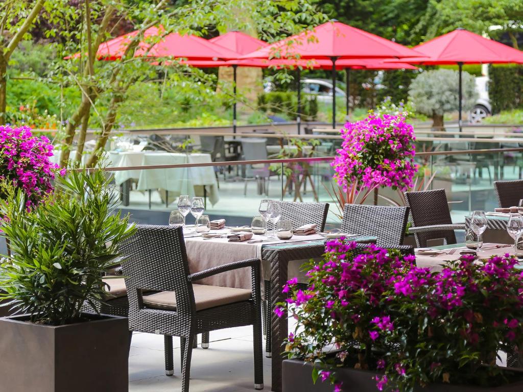 卢森堡Le Royal Hotels & Resorts Luxembourg的天井上配有桌椅和粉红色鲜花