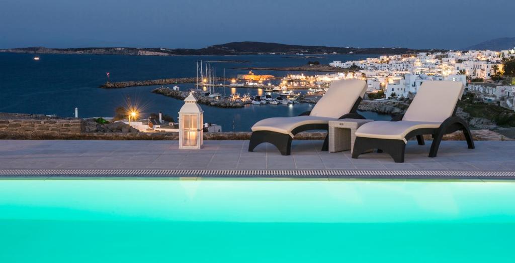 纳乌萨Villa Irini的一个带两把椅子的游泳池,享有海港的景色