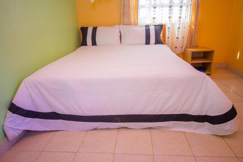内罗毕Airport Gate View Hotel的卧室配有白色大床,铺有蓝色和白色的床单
