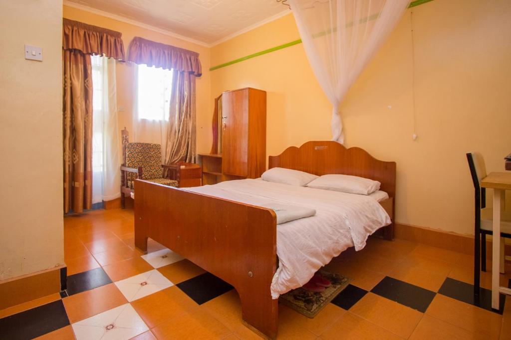 KakamegaJamindas Paradise Motel的一间卧室配有一张床,铺有一个 ⁇ 板地板