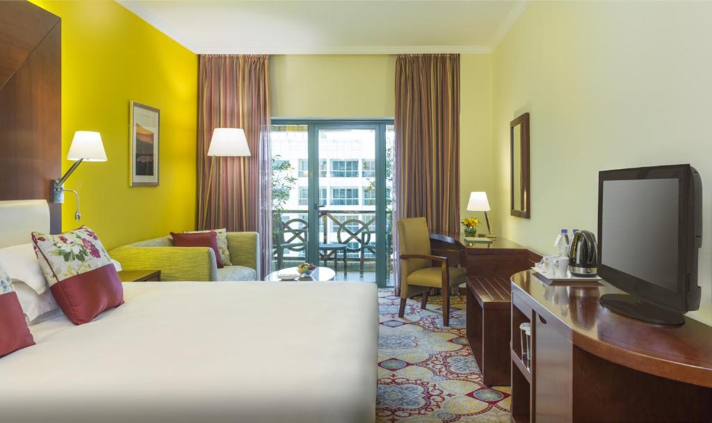 迪拜迪拜德伊勒珊瑚酒店的酒店客房配有一张床、一张书桌和一台电视。