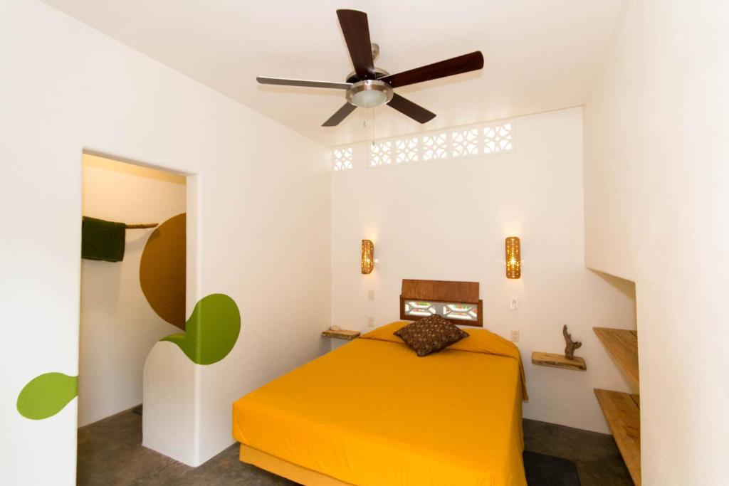 波波约Red Pepper Popoyo的一间卧室配有黄色的床和吊扇