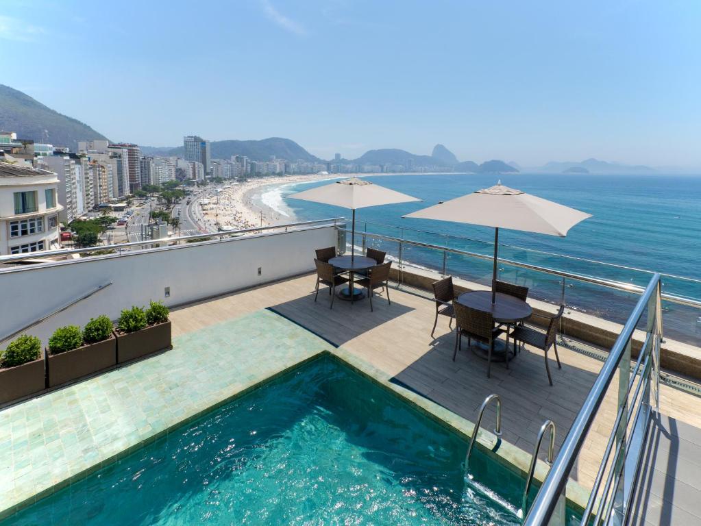 里约热内卢奥拉克帕卡巴那酒店的阳台设有游泳池、桌子和遮阳伞