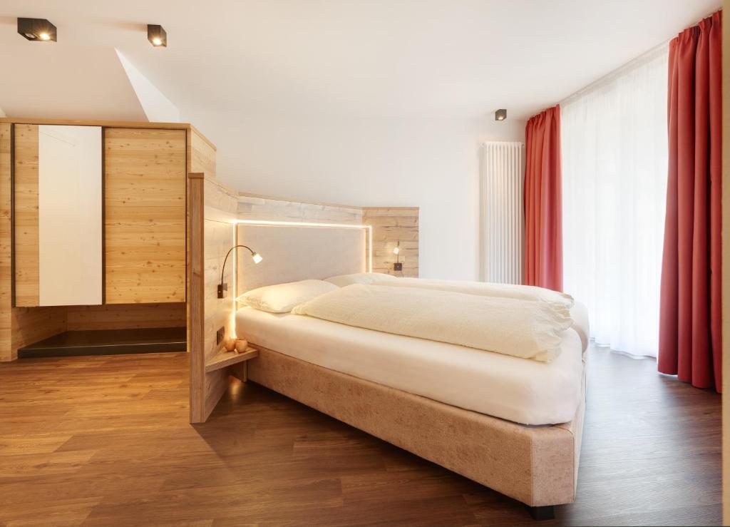 泰塞罗Hotel Al Cervo的卧室配有白色大床和红色窗帘