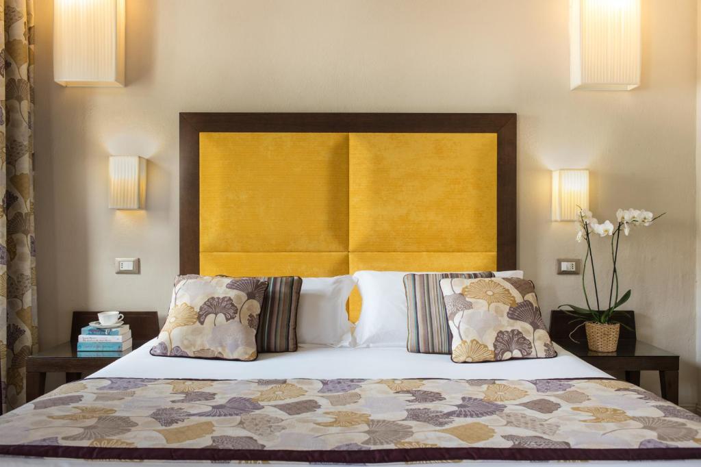 佛罗伦萨佩尔塞奥酒店的一间卧室配有一张带黄色床头板和枕头的床。