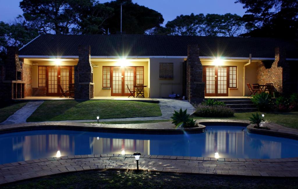 伊丽莎白港African Aquila Guest Lodge的一座晚上设有游泳池的房子