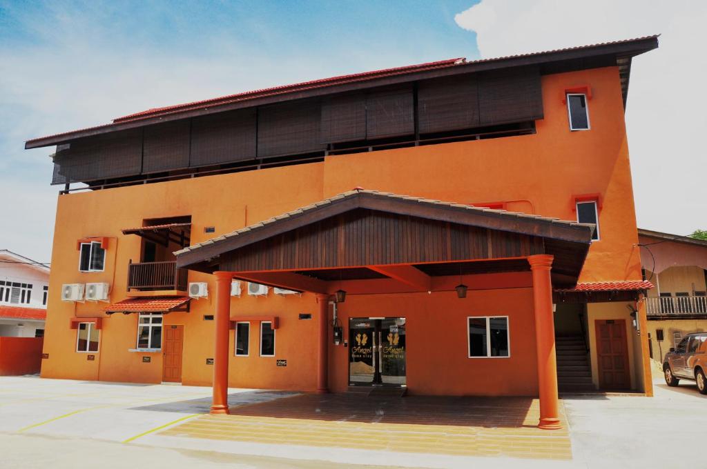 瓜拉丁加奴天使酒店的一座橙色的建筑,前面设有停车场