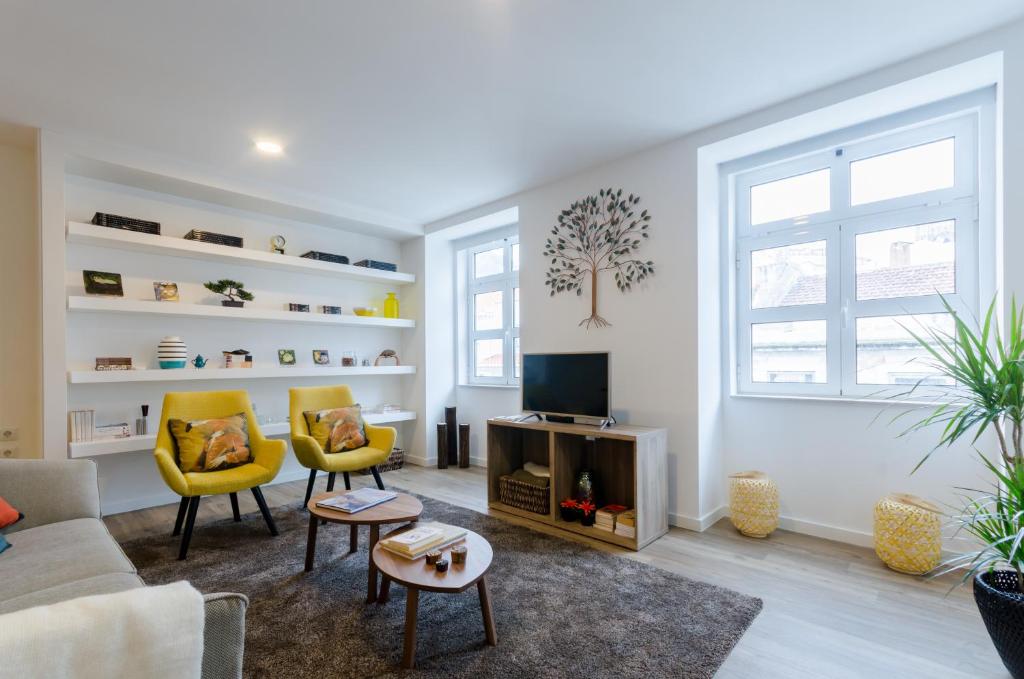 里斯本洛格公寓的客厅配有2把黄色椅子和电视