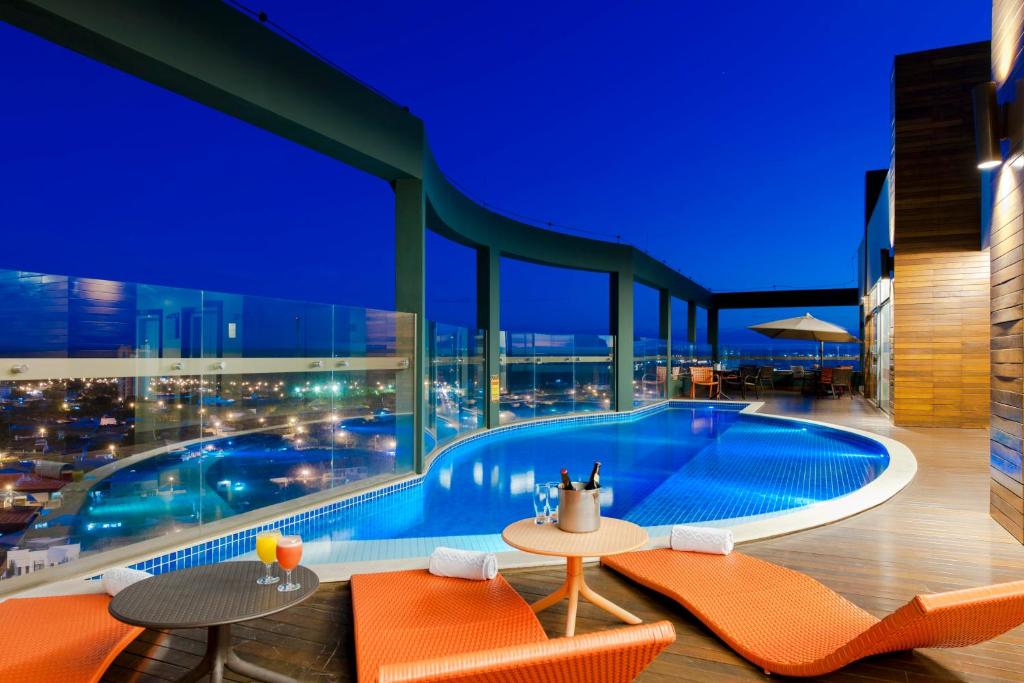 龙多诺波利斯伦多诺波利斯舒适套房酒店的夜间在建筑物屋顶上的游泳池