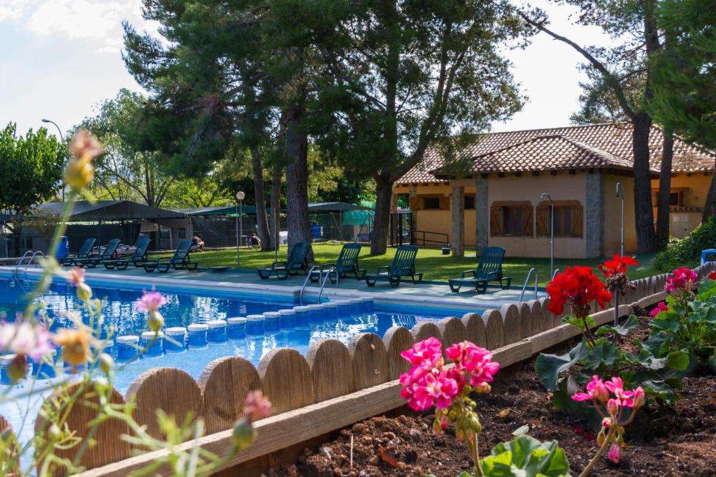 纳瓦哈斯阿尔托米拉露营别墅酒店的一座带房子和鲜花的游泳池