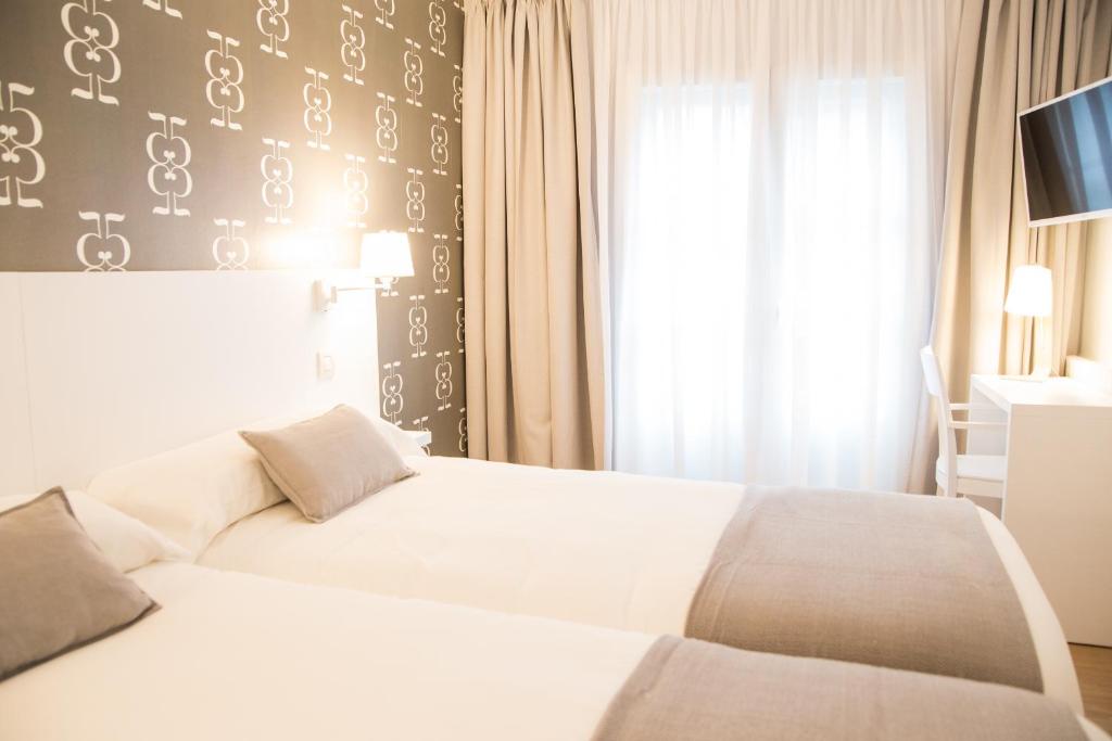圣地亚哥－德孔波斯特拉Hostal Suso的酒店客房设有两张床和窗户。