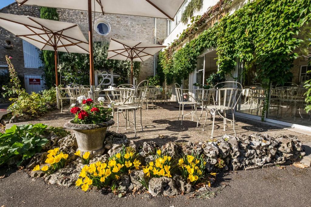 博讷Hostellerie De Bretonnière - Groupe Logis Hotels的一个带桌椅、鲜花和遮阳伞的庭院