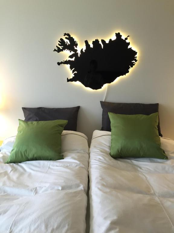 凯夫拉维克海景公寓别墅的一间卧室配有两张床,提供白色的床单和绿色的枕头