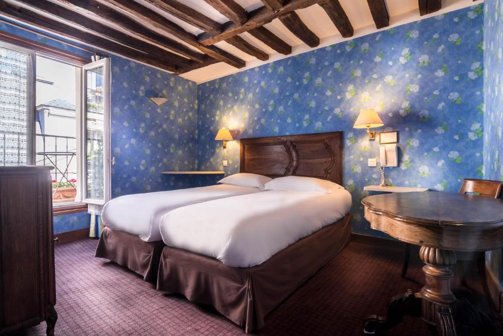 巴黎杜黎斯酒店的一间卧室配有一张大床和一张桌子