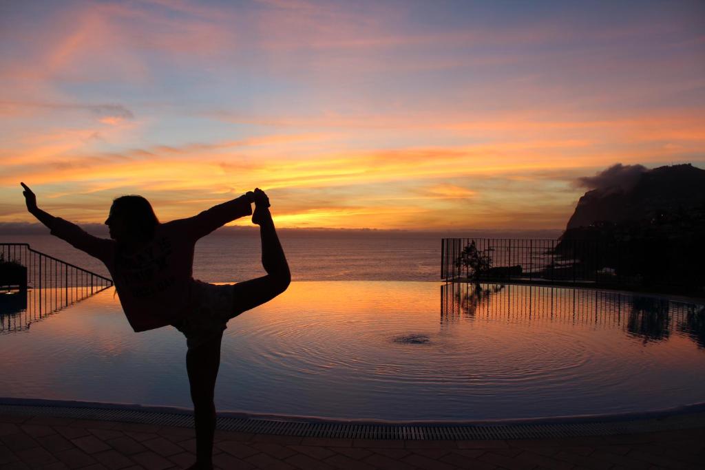 丰沙尔Atlantic Ocean View Apartment的一名在游泳池前做瑜伽姿势的女人
