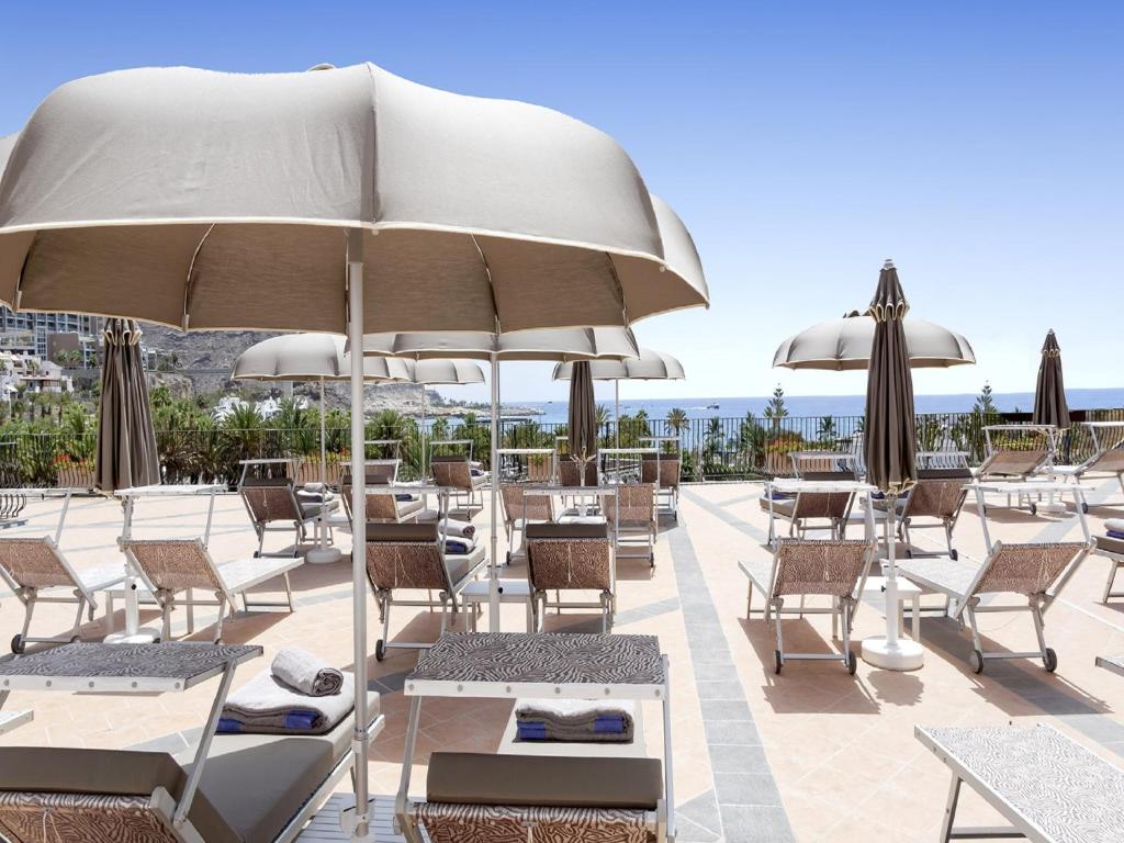 库拉海滩Idyll Suites - Adults Only的一个带桌椅和遮阳伞的庭院