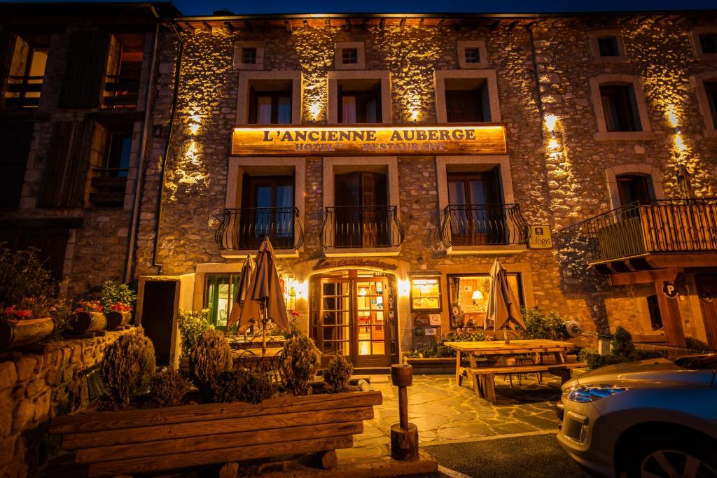 布齐耶比利牛斯2000Logis Hôtel Restaurant L'ancienne Auberge的一家在晚上在前面有标志的酒店