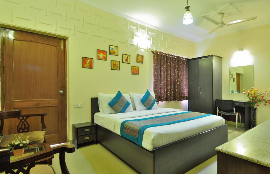 新德里国际贝索娜酒店的酒店客房配有一张床、一张书桌和一张书桌。