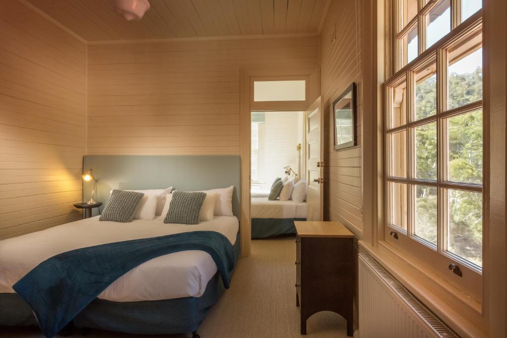 Yarrangobilly亚仁勾比利岩洞之家度假村的一间卧室设有两张床和两个窗户。