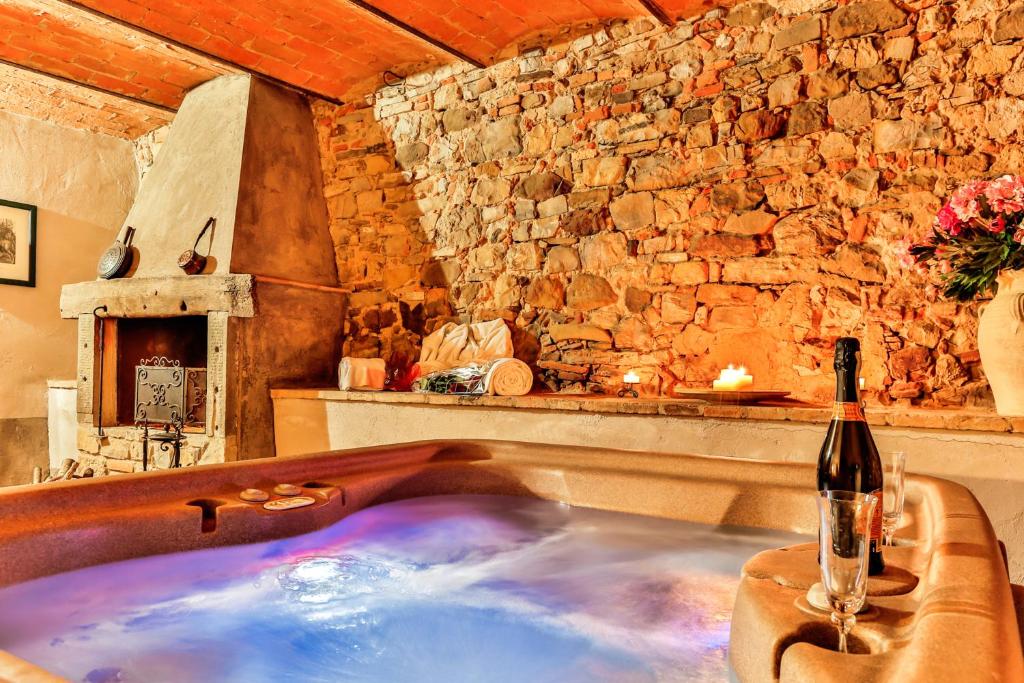 佩尔吉内-瓦尔达诺La Miccia的客房内的浴缸,备有一瓶葡萄酒