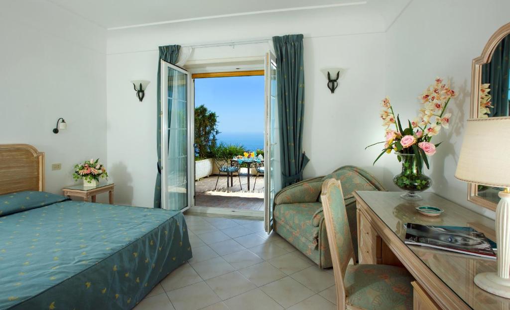 阿纳卡普里戴吉尔索密娜酒店的一间卧室配有一张床、一张沙发和一张桌子
