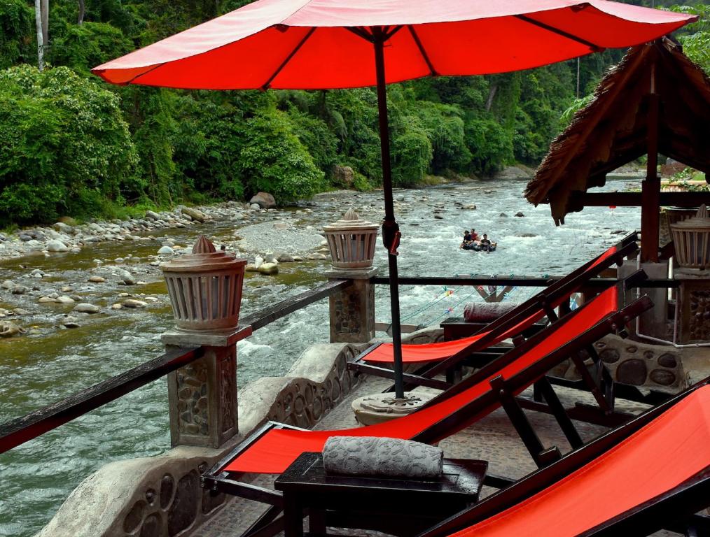 武吉拉旺武吉拉旺生态住宿加早餐旅馆的一条带遮阳伞和椅子的船和一条河流