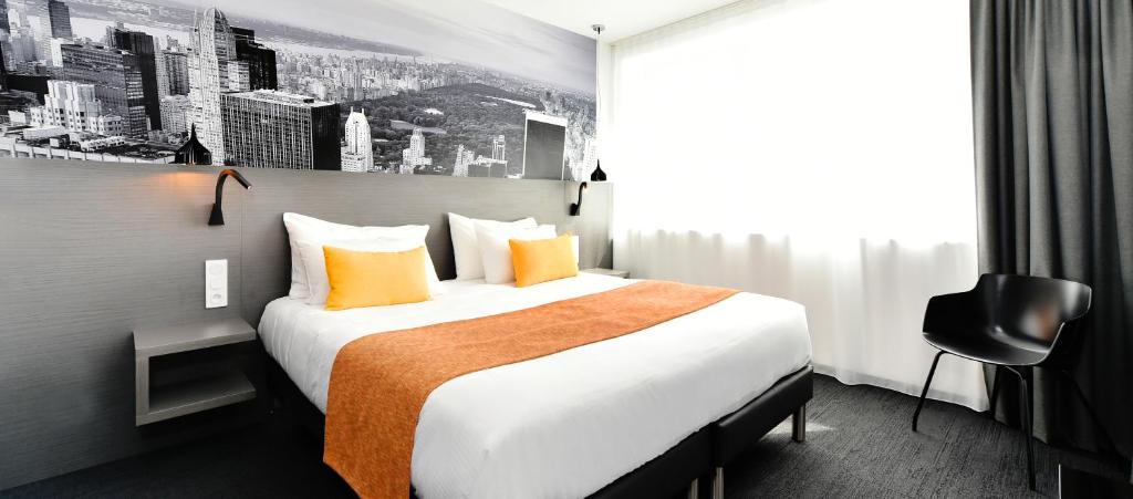拉罗谢尔中央公园酒店及Spa中心的酒店客房配有一张带橙色枕头的大床