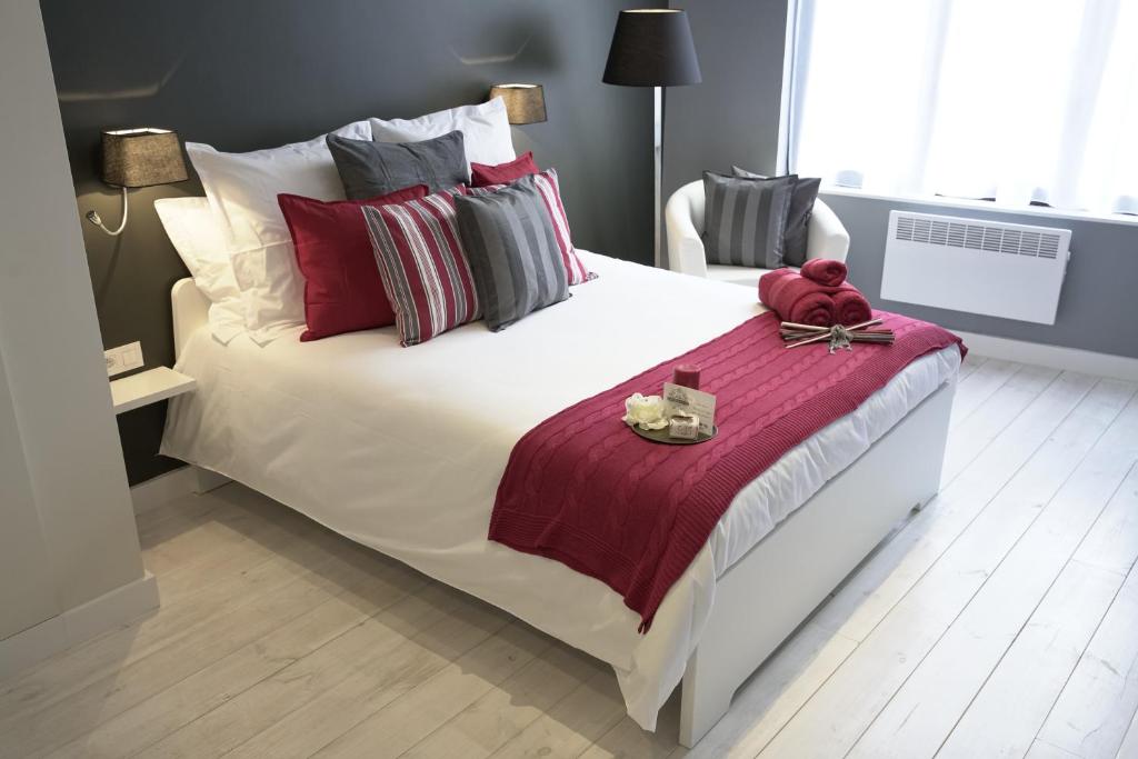 布鲁塞尔游走布鲁塞尔住宿加早餐旅馆的卧室配有一张白色大床,提供红色和灰色的枕头